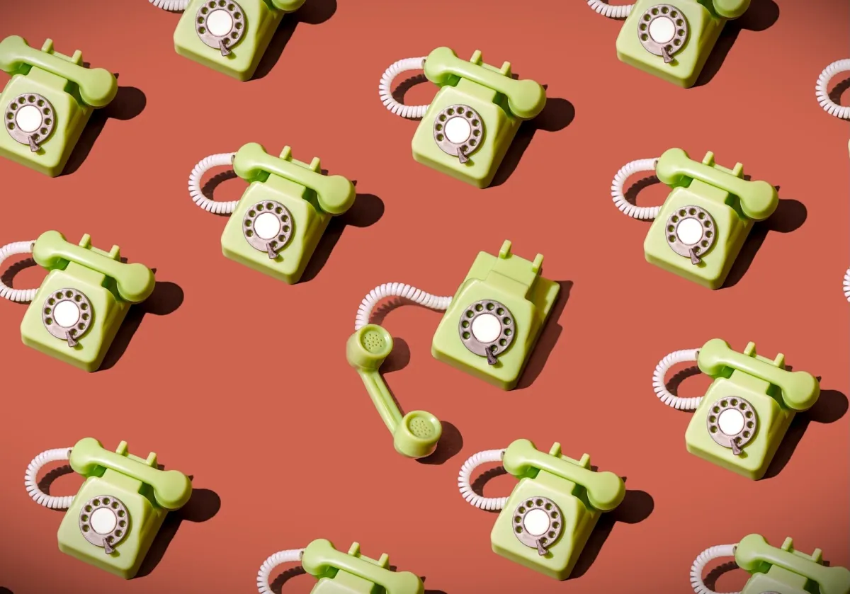 High angle view of some vintage green rotary telephones arranged on a brown background, showcasing retro communication technology with a nostalgic and artistic flair
